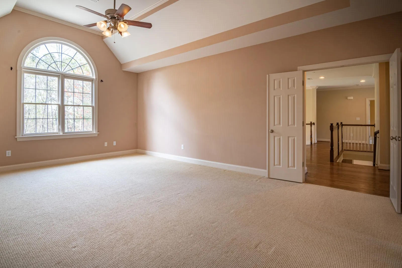 New wall-to-wall beige carpet in a bright bedroom with an arched window