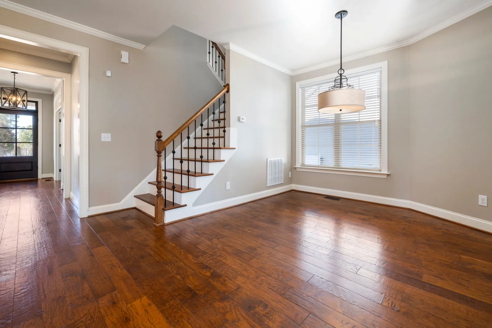 Warm hardwood flooring running through a bright DMV living room and up the staircase