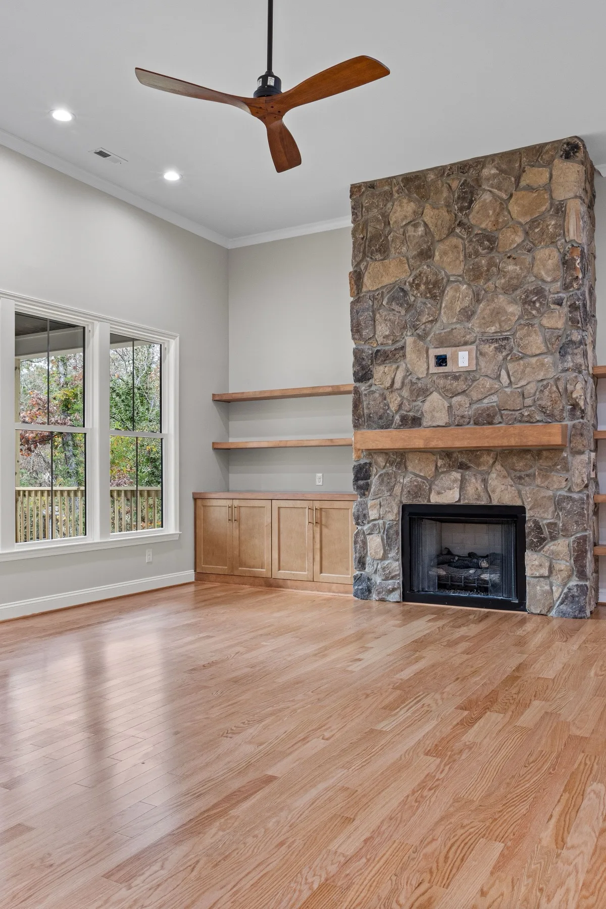 New red oak hardwood floor installed through an open living room with stone fireplace — Fairland, MD area