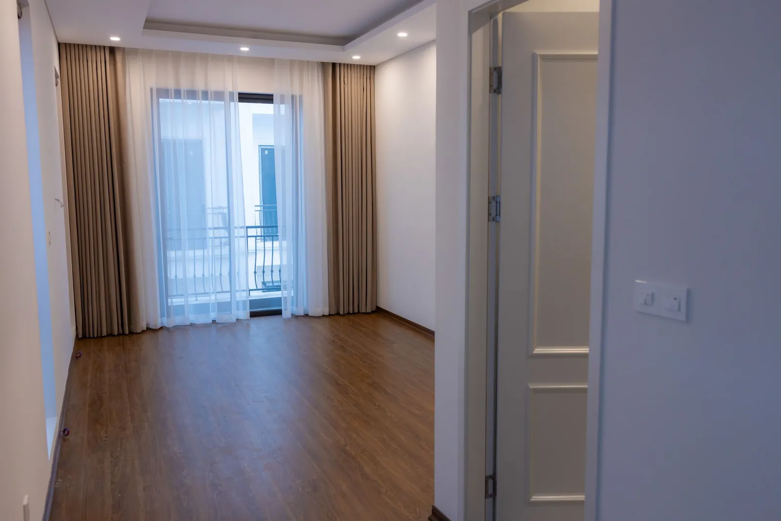 Wood-look plank flooring in an empty bedroom with a balcony door
