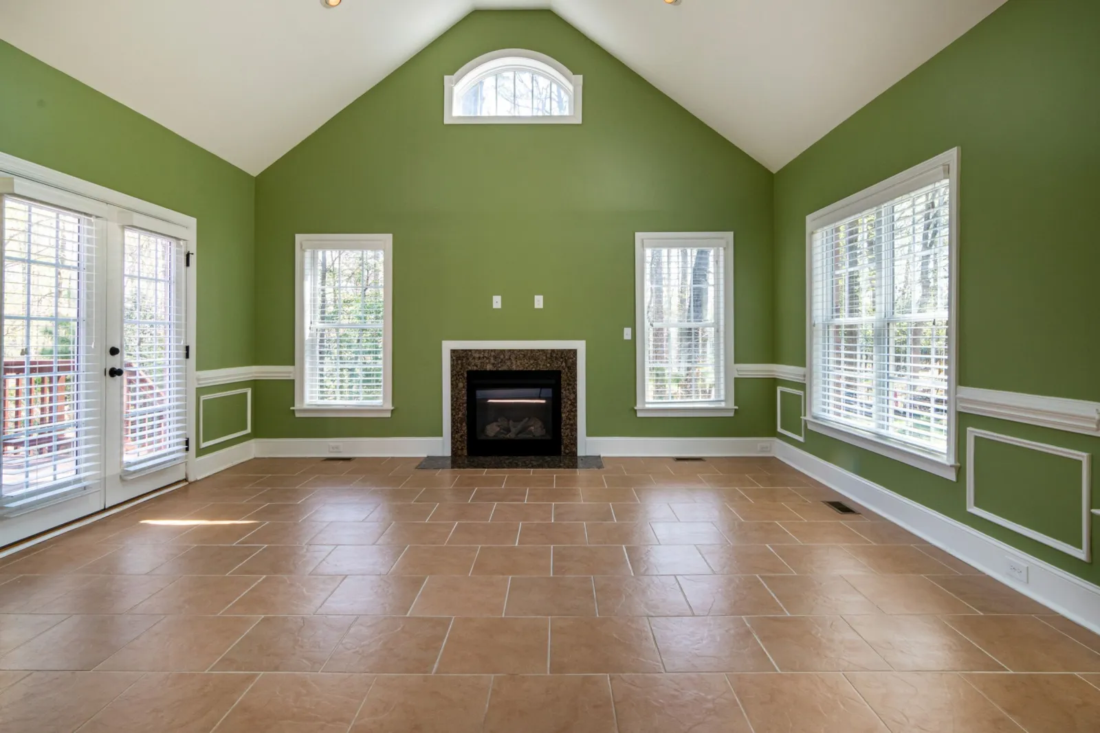 Large tan floor tiles in an offset pattern across a vaulted great room with a fireplace
