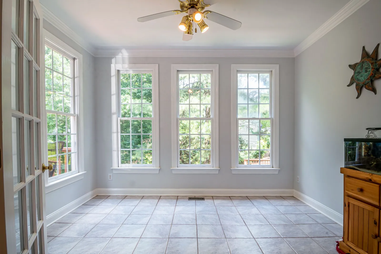 Gray ceramic tile floor in a sunroom with tall windows looking out on trees